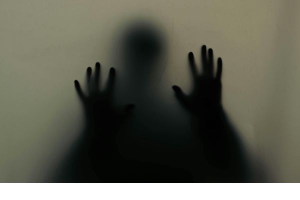 a shadow of a man with his hands on a window